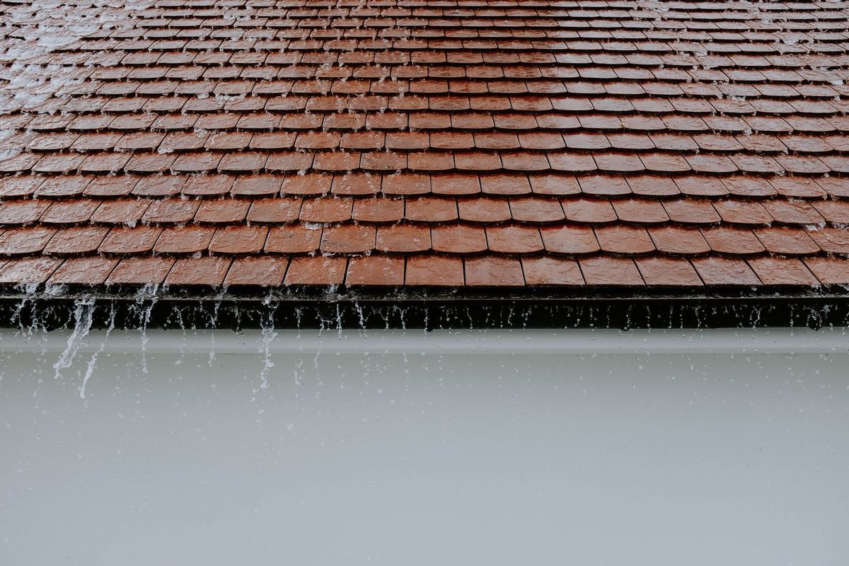Rain pouring off a tile roof